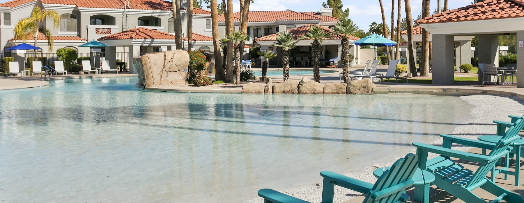 a pool with chairs and umbrellas by a building