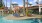 a pool with chairs and umbrellas by a building