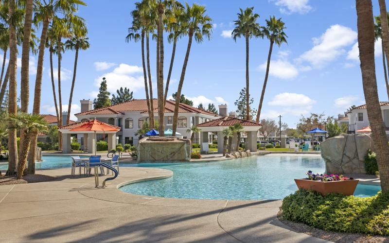 a pool with palm trees and a building in the background