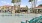 a pool with chairs and umbrellas by a building