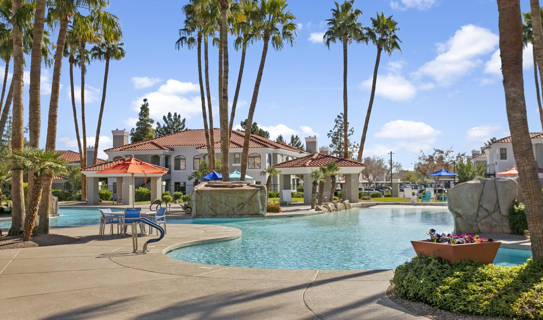 a pool with palm trees and a building in the background