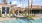 a pool with chairs and umbrellas by a building